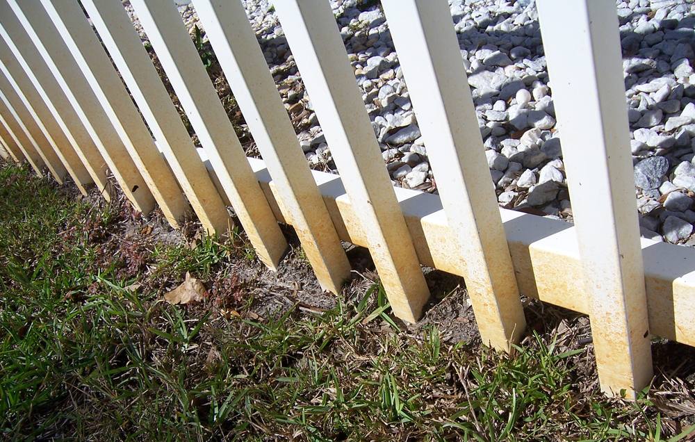 White vinyl fence discolored with algae before cleaning
