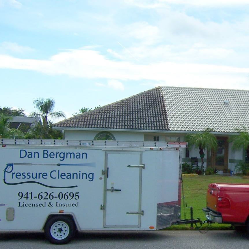 The Dan Bergman Pressure Cleaning trailer parked outside a Florida home whose barrel-tile roof is part-way through a soft wash