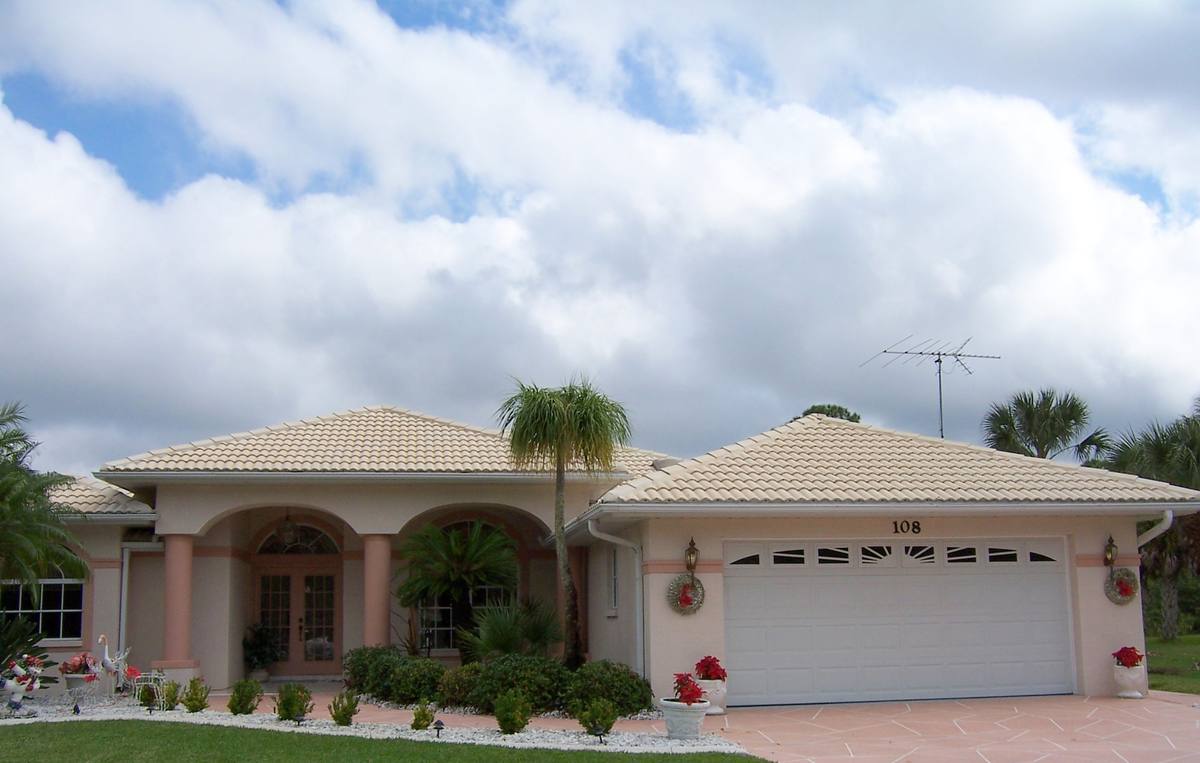The same Florida home after cleaning, tile roof and stucco bright under a blue sky