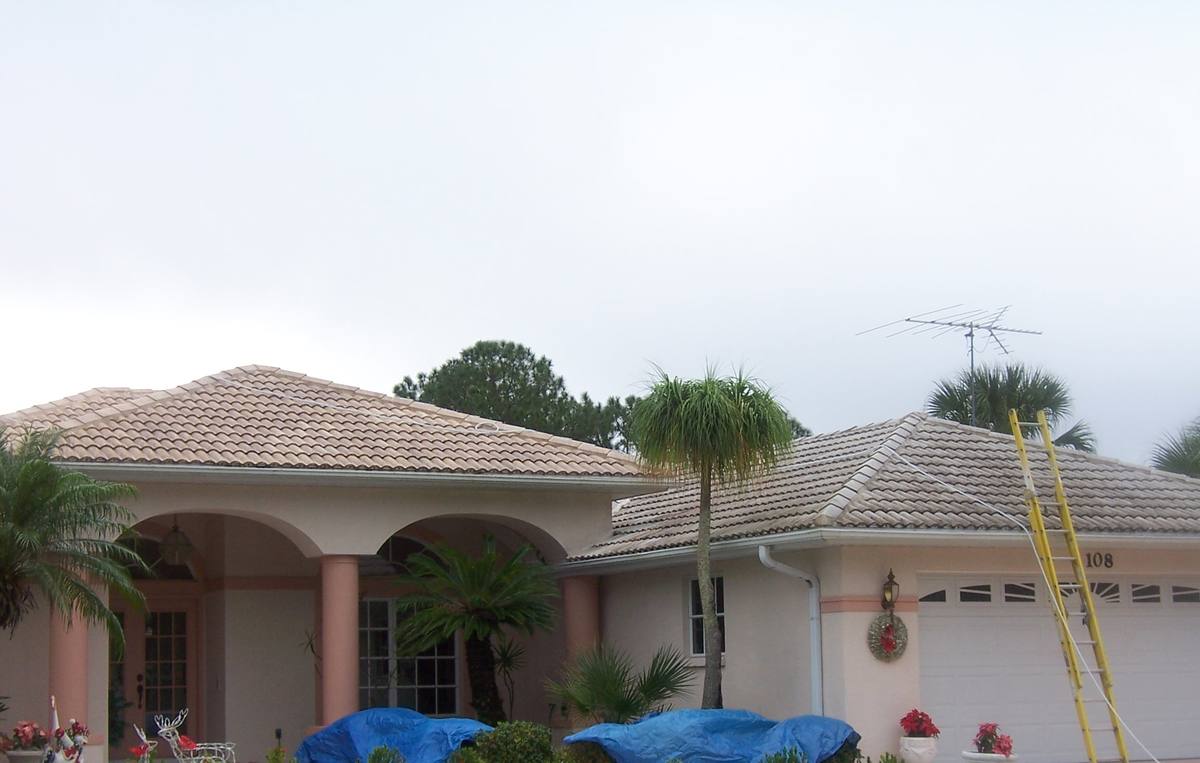 Florida home before roof cleaning, with the landscaping tarped off for protection